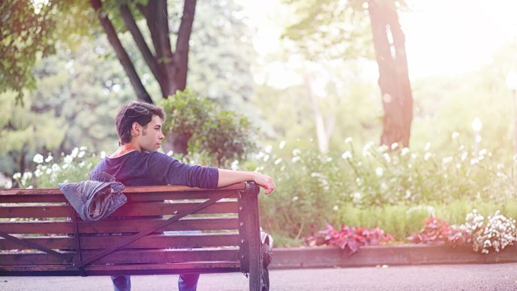 Mężczyzna siedzący na ławce w parku, zamyślony